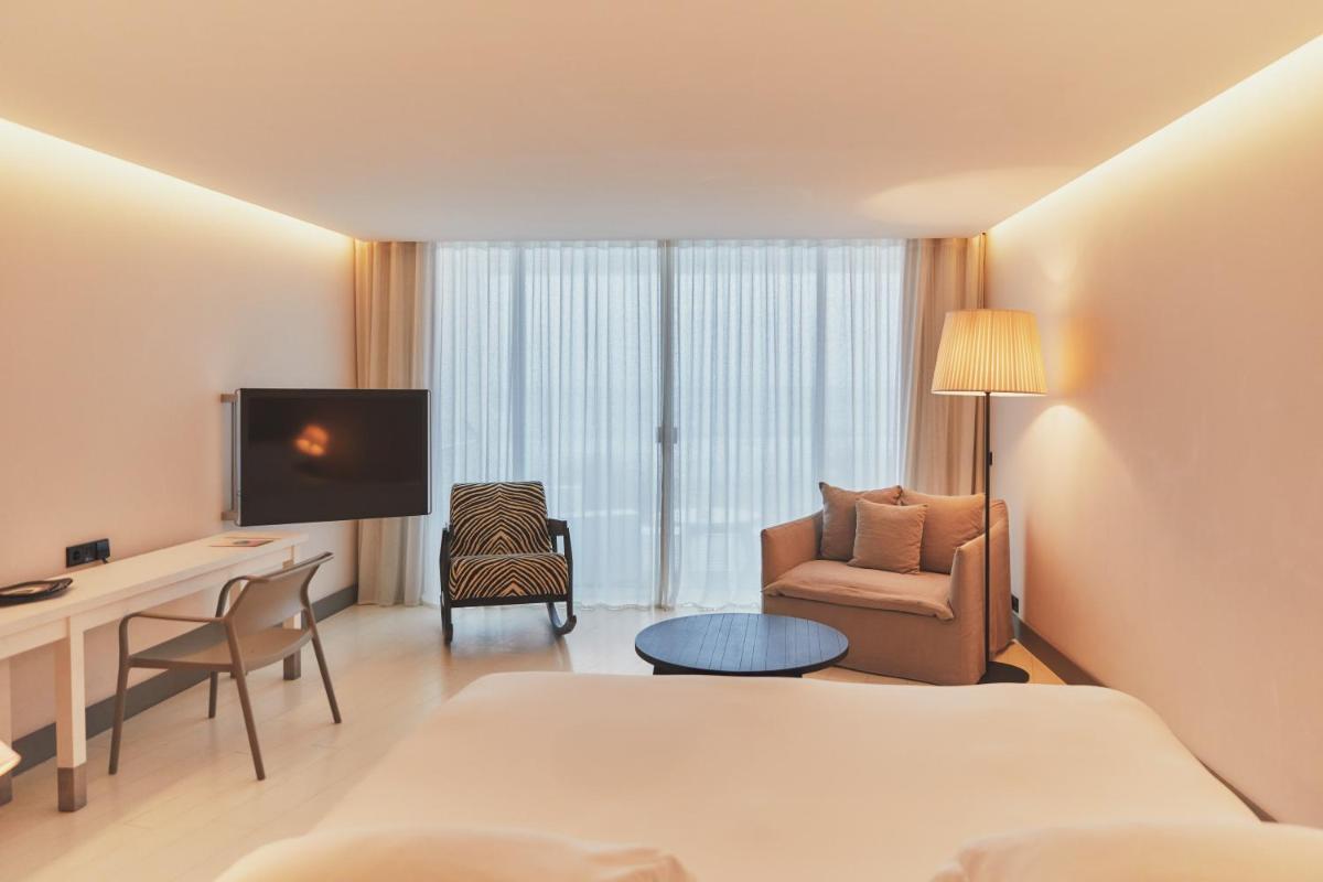 une chambre d'hôtel avec un lit, un bureau et une télévision dans l'établissement Hôtel Plage Palace & Spa, à Palavas-les-Flots