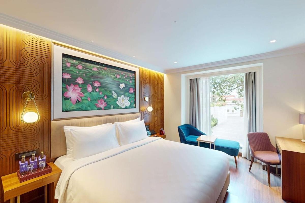 a hotel room with a white bed and a window at Radisson Blu Hotel & Suites GRT Chennai in Chennai