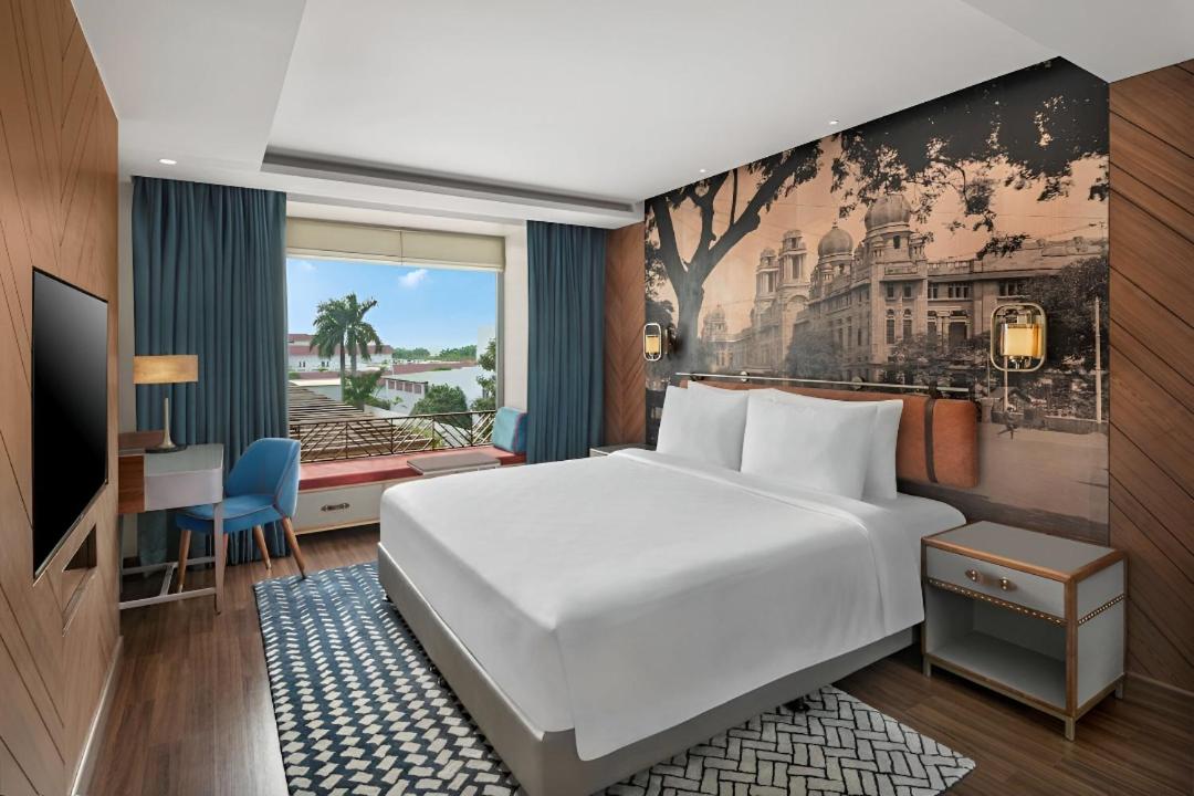 a hotel room with a white bed and a desk at Radisson Blu Hotel & Suites GRT Chennai in Chennai