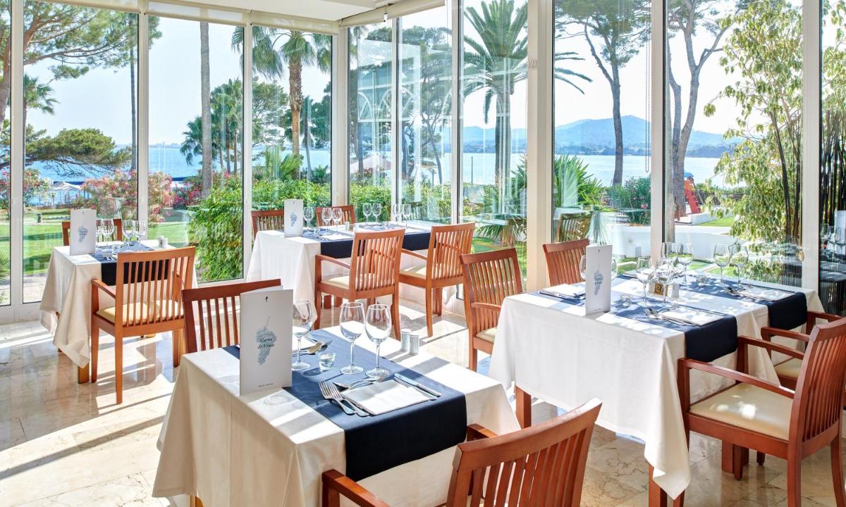Un comedor con mesas y sillas y ventanas. en Hipotels Eurotel Punta Rotja Spa-Golf, en Costa des Pins