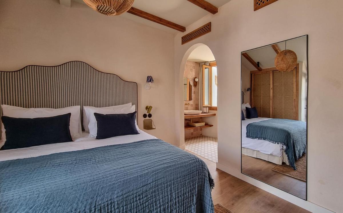 Un dormitorio con una cama grande y un espejo. en Nomad Hotel & Spa Altea, en Altea