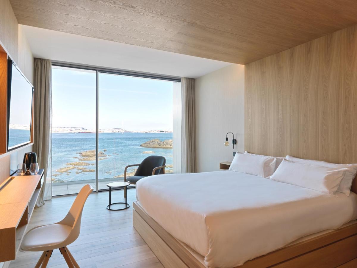 Una habitación de hotel con una cama y una ventana grande. en Noa Boutique Hotel, en Santa Cruz de Oleiros