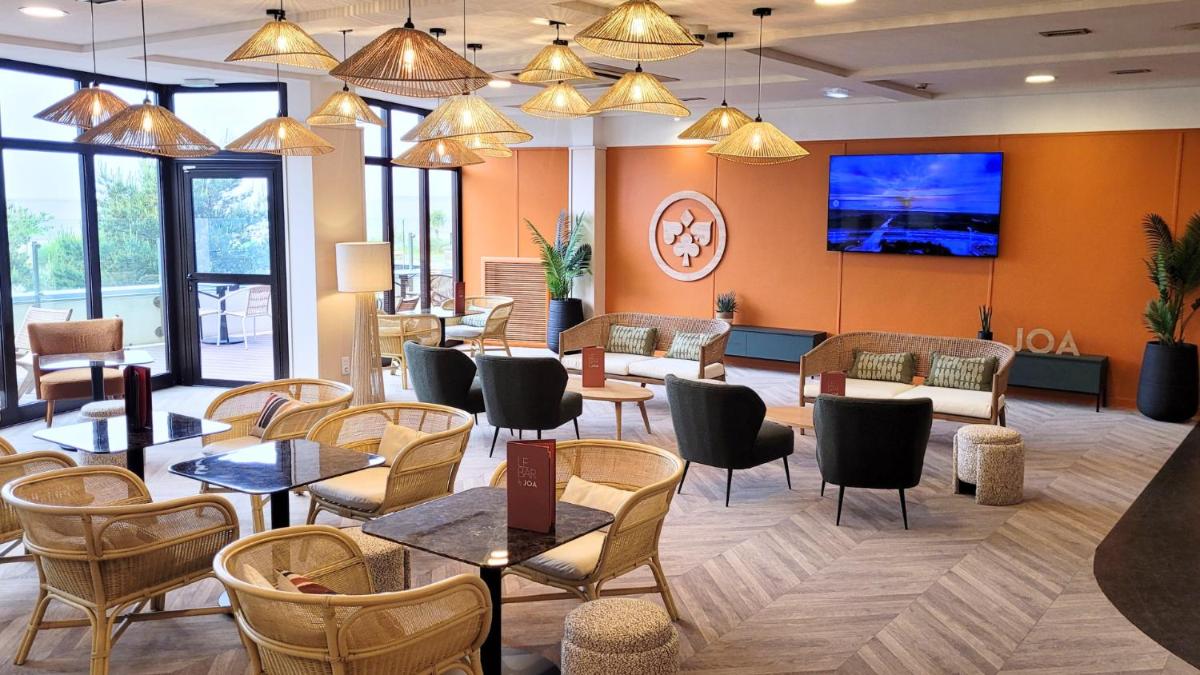 une salle d'attente avec des tables et des chaises et une télévision dans l'établissement Hôtel Spa du Beryl St Brévin l'Océan, à Saint-Brévin-les-Pins