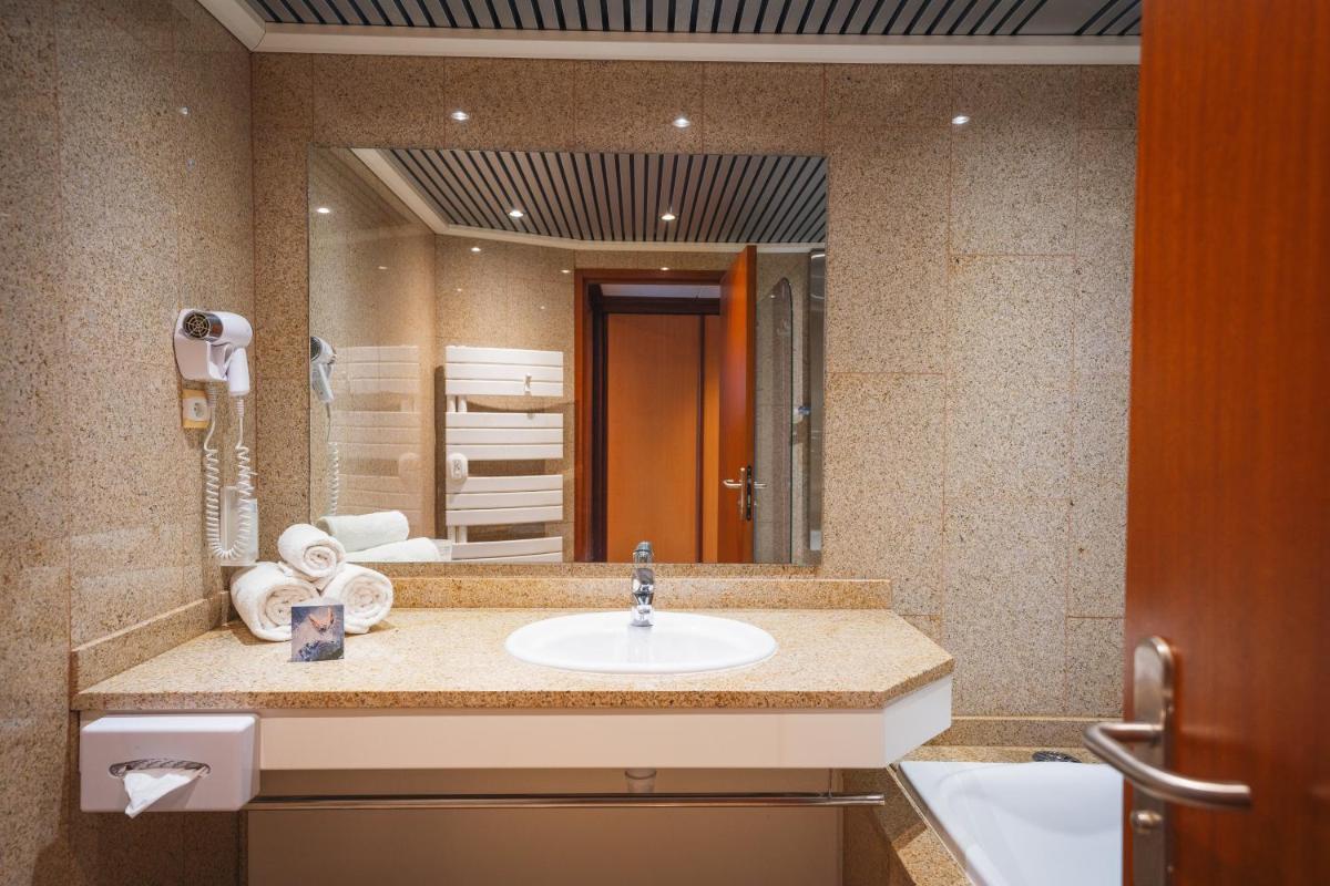 une salle de bain avec un lavabo et un grand miroir dans l'établissement Hôtel Spa du Beryl St Brévin l'Océan, à Saint-Brévin-les-Pins