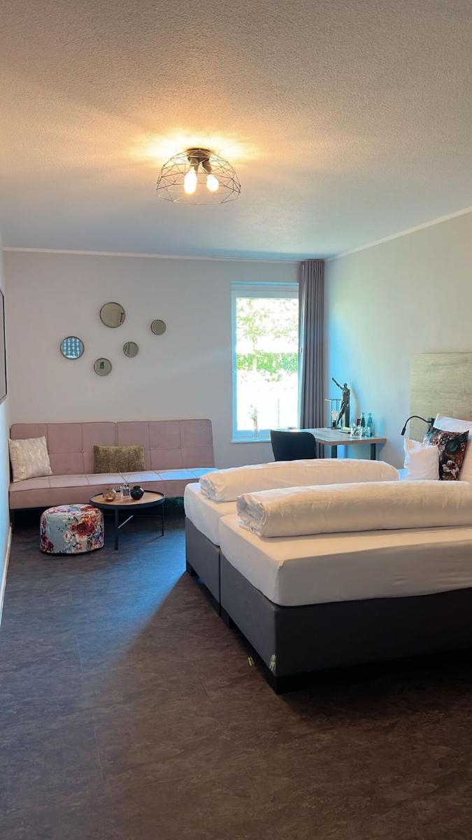 ein großes Schlafzimmer mit 2 Betten und einem Sofa in der Unterkunft Motel Hasetal in Löningen
