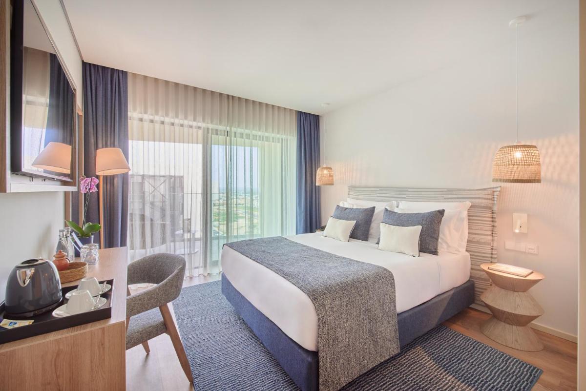 um quarto de hotel com uma cama e uma janela grande em The Editory by the Sea Lagos em Lagos