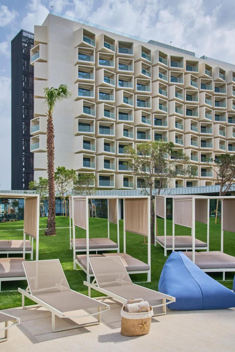 um hotel com espreguiçadeiras e um prédio em The Editory by the Sea Lagos em Lagos