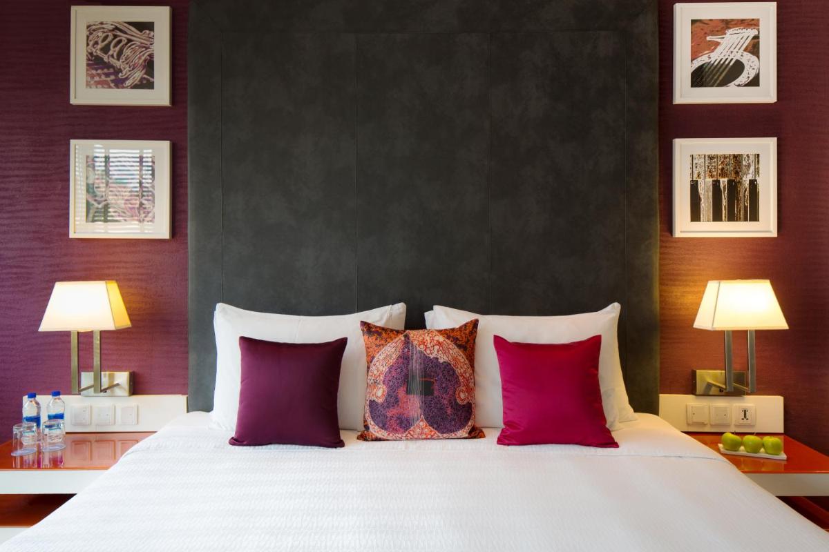a bedroom with a large white bed with purple walls at Hard Rock Hotel Goa Calangute in Calangute