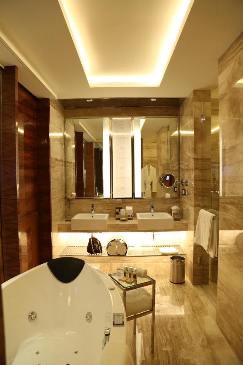 a bathroom with a tub and a large mirror at Taj City Centre Gurugram in Gurgaon