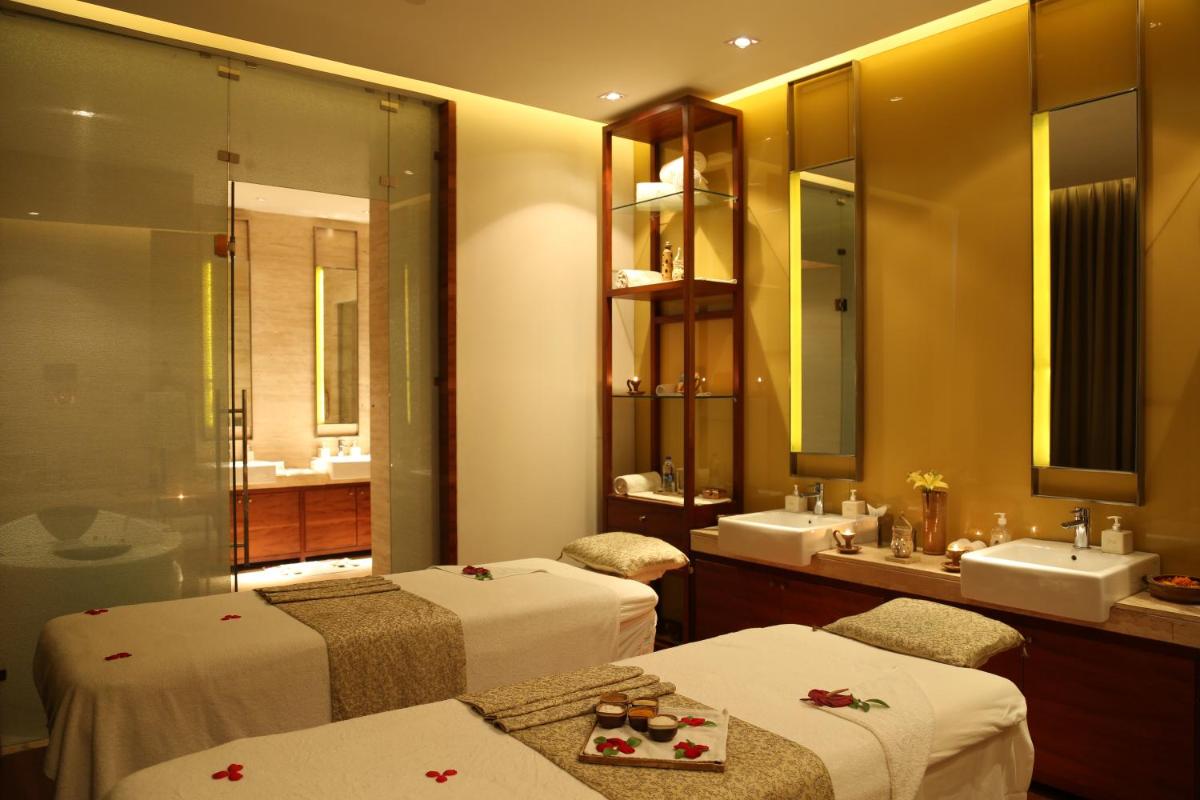 a room with two beds and a bathroom with a sink at Taj City Centre Gurugram in Gurgaon