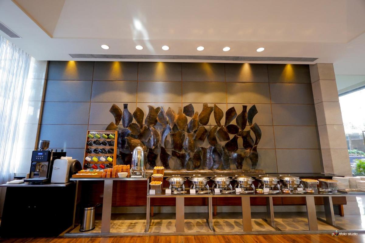 a restaurant with a counter with food on a wall at Crowne Plaza Today Gurugram by IHG in Gurgaon