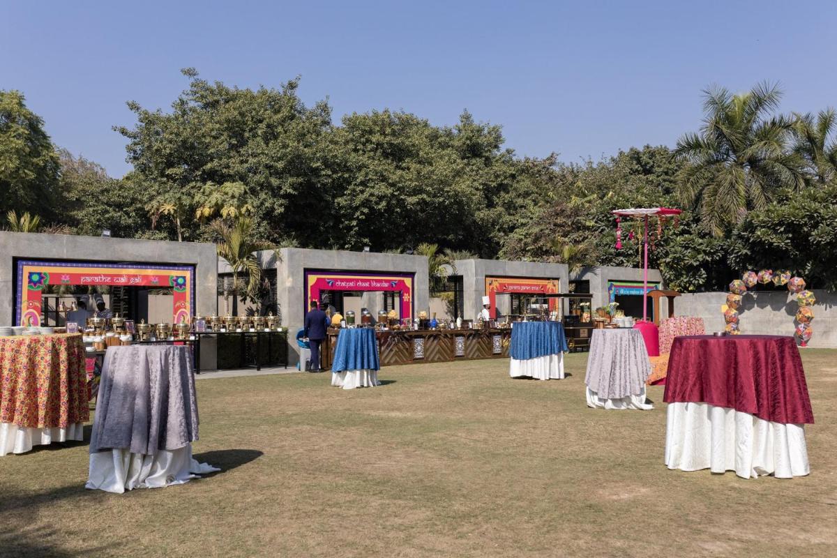 a group of tables in a field with people standing around at Crowne Plaza Today Gurugram by IHG in Gurgaon