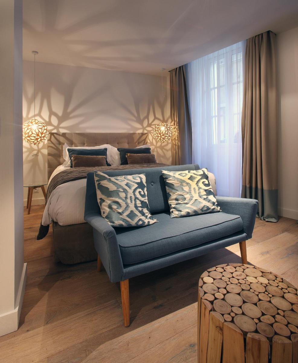 une chambre avec un lit et un canapé bleu dans l'établissement Petit Hôtel Confidentiel, à Chambéry