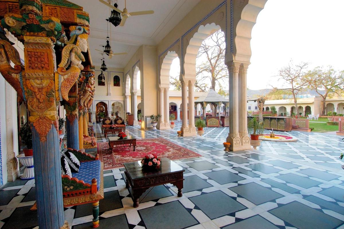 a lobby of a building with a person sitting on a bench at The Raj Palace (Small Luxury Hotels of the World) in Jaipur