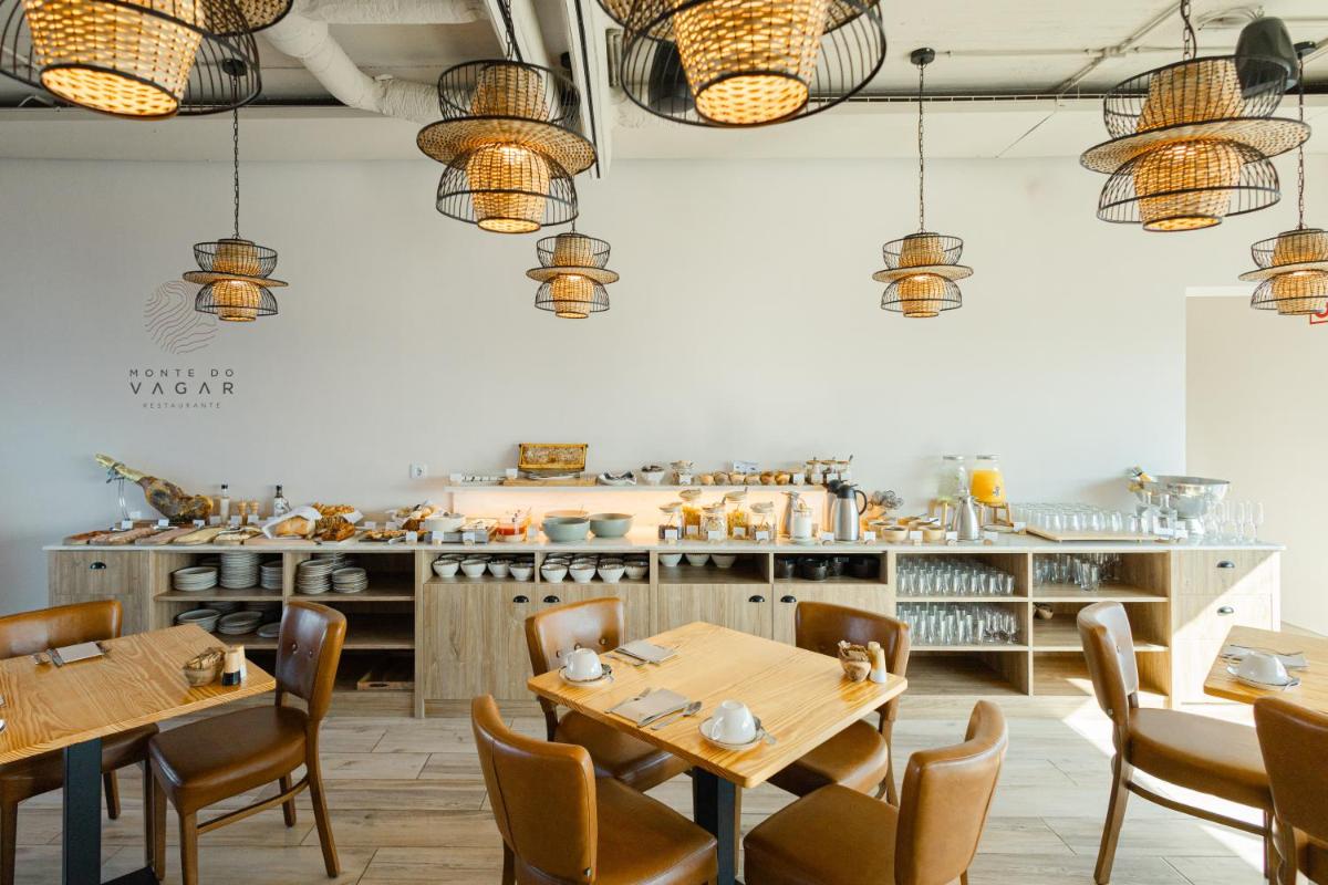 um restaurante com mesas e cadeiras de madeira e uma cozinha em Sleep & Nature Hotel em Lavre
