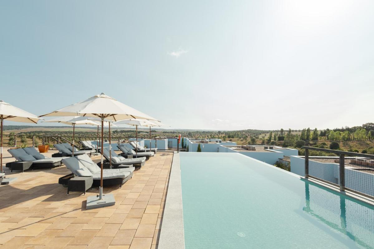 uma piscina com cadeiras e guarda-sóis em um prédio em Sleep & Nature Hotel em Lavre