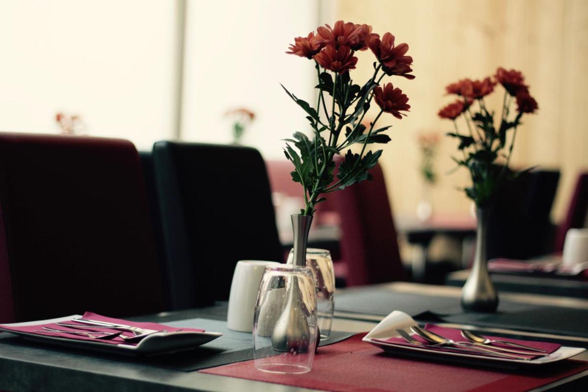 une table avec un vase avec des fleurs rouges dans l'établissement Hôtel Brésil Opéra SPA, à Paris