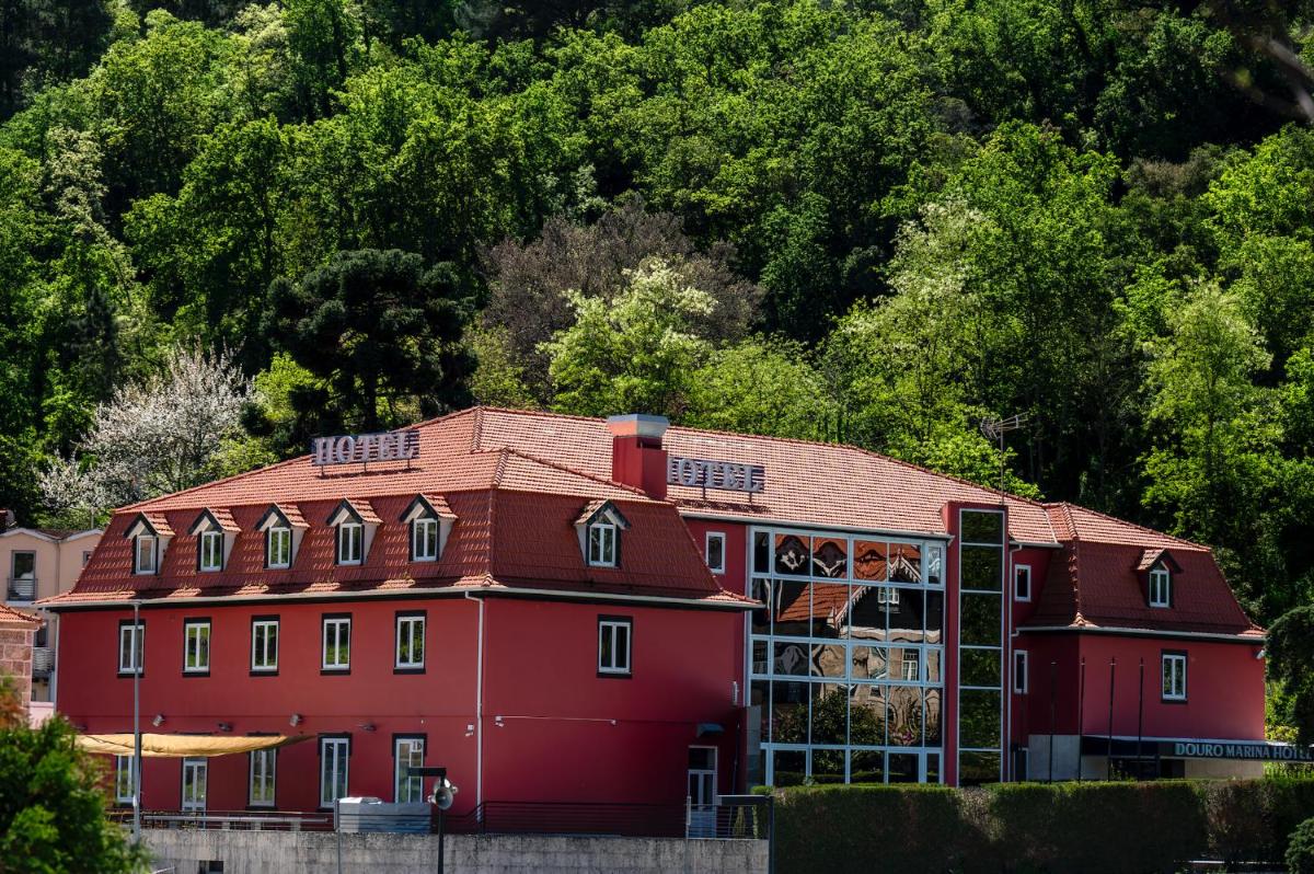 um grande edifício vermelho com árvores ao fundo em Douro Marina Hotel & SPA em Resende