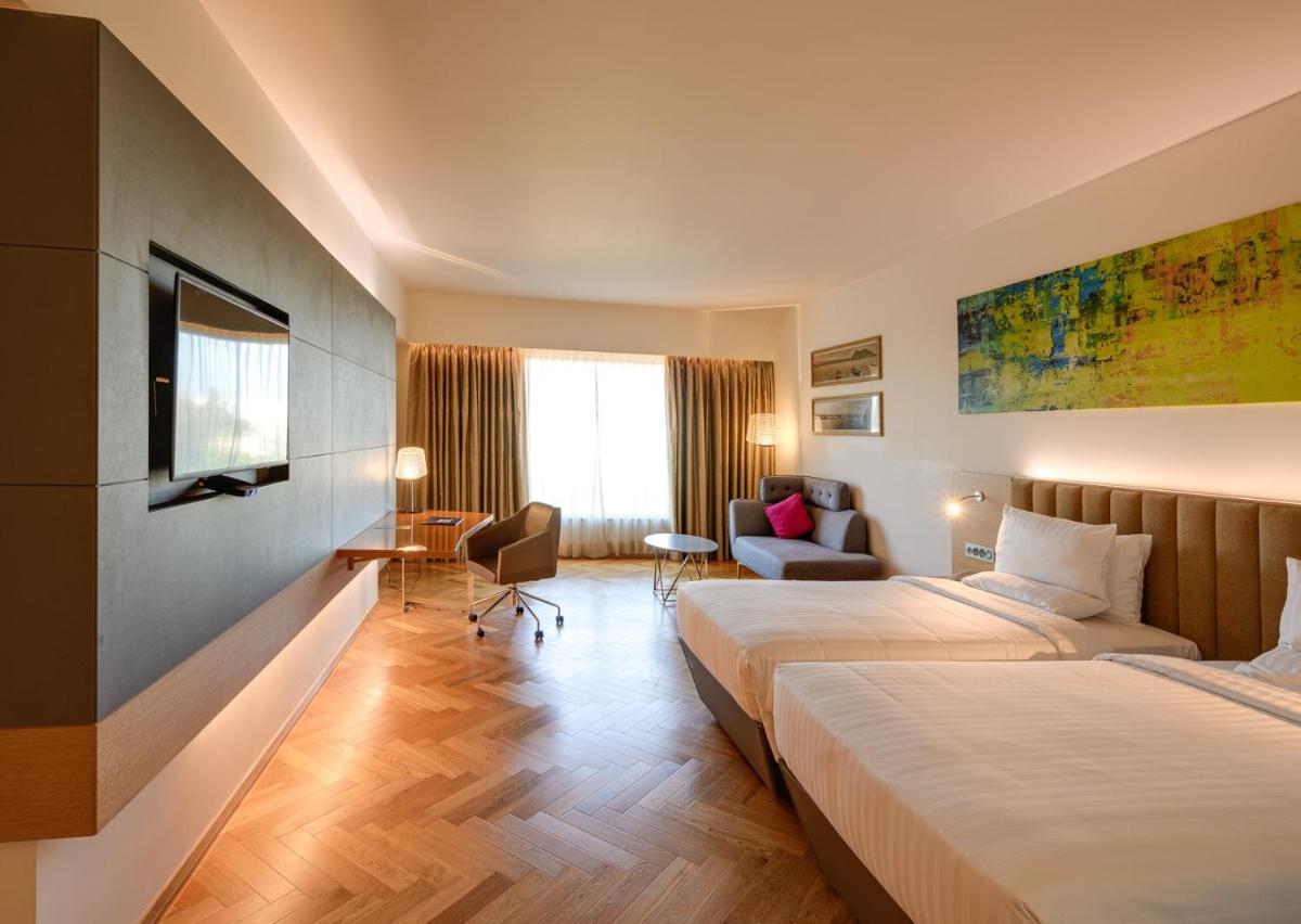 a hotel room with two beds and a couch at Novotel Vijayawada Varun in Vijayawāda
