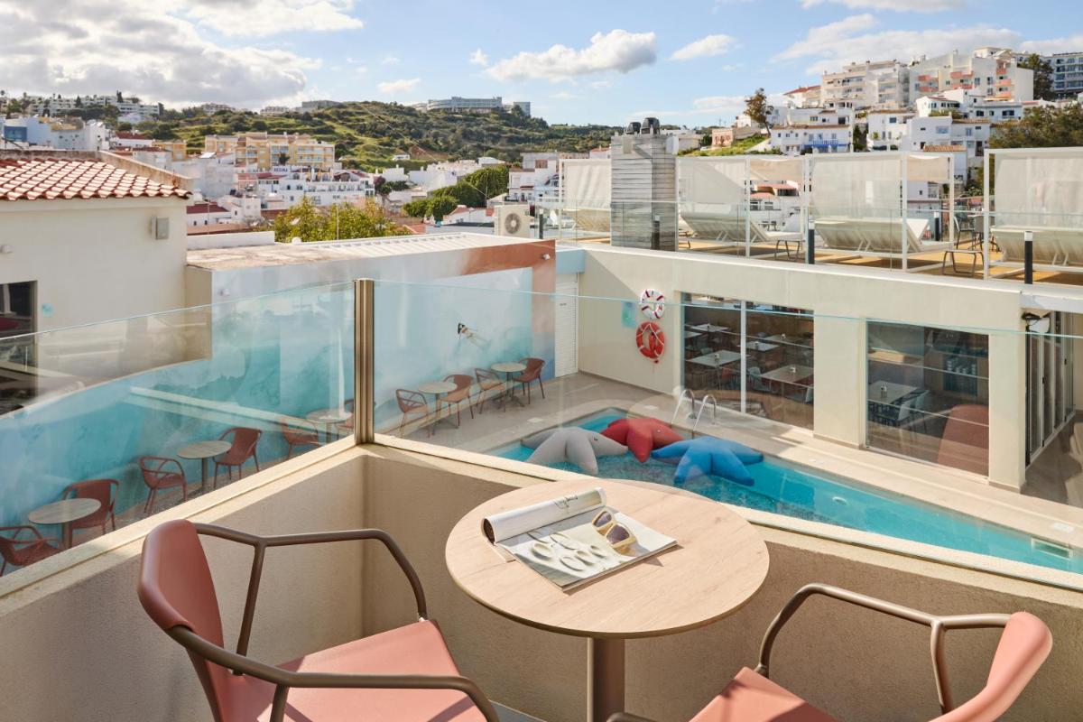 um quarto com uma varanda com uma mesa e cadeiras em Hotel Indigo Albufeira by IHG em Albufeira