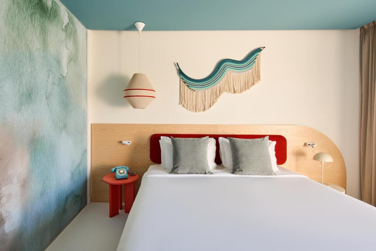 um quarto com uma cama grande e uma cabeceira vermelha em Hotel Indigo Albufeira by IHG em Albufeira