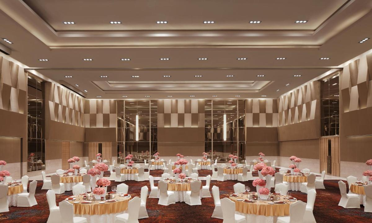 a large room with tables and chairs with pink flowers at Taj Bangalore in Devanahalli-Bangalore