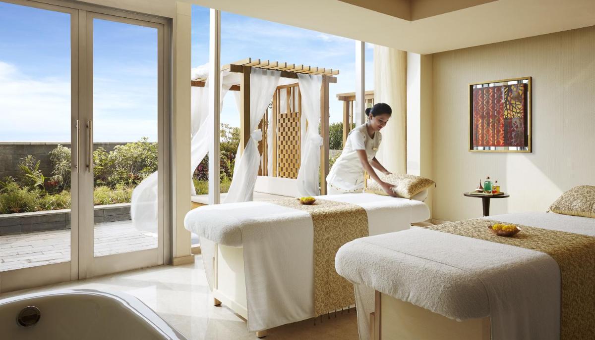 a woman in a room with two beds and a window at Taj Bangalore in Devanahalli-Bangalore