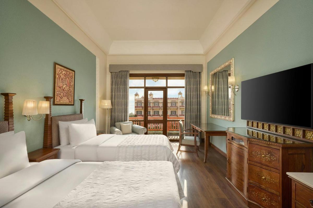 a hotel room with two beds and a flat screen tv at Le Meridien Jaipur Resort & Spa in Jaipur