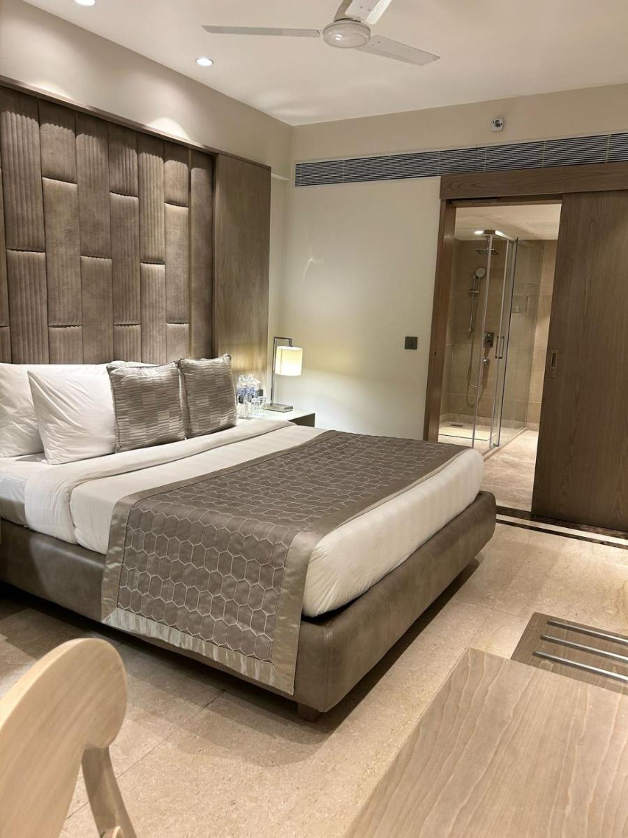 a bedroom with a large bed and a glass door at Jaypee Siddharth in New Delhi a bedroom with a large bed and a glass door at Jaypee Siddharth in New Delhi