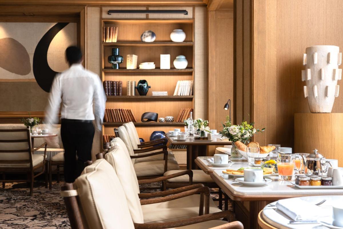 une personne entrant dans une salle à manger avec des tables dans l'établissement Esprit Saint Germain, à Paris