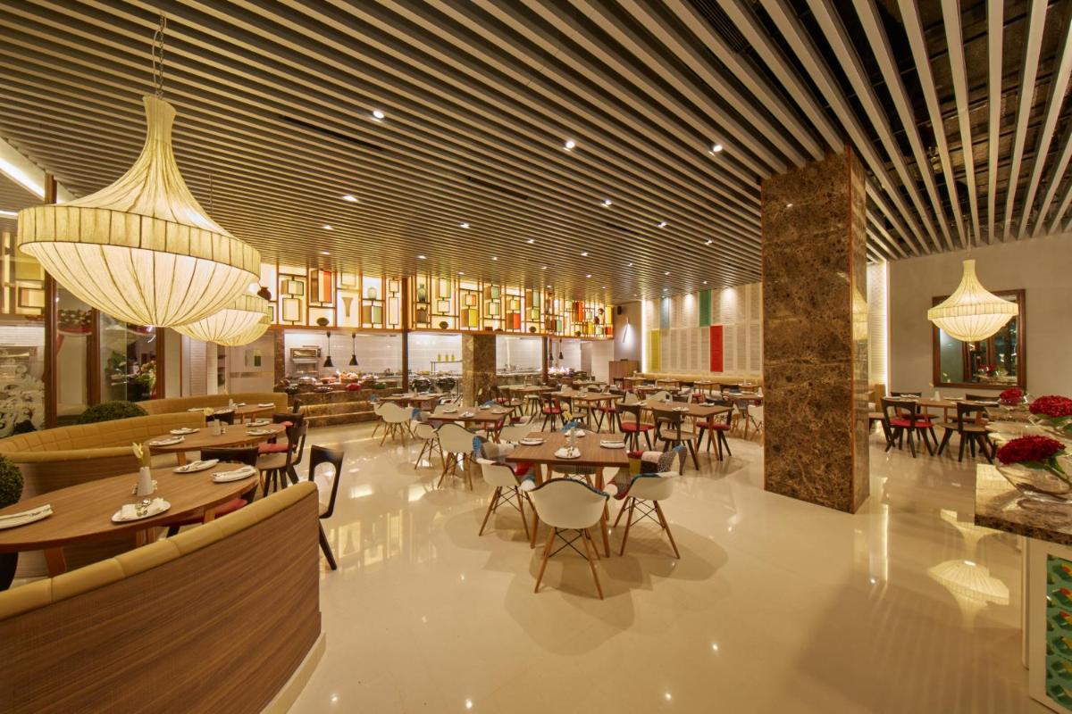 a restaurant with tables and chairs and chandeliers at Hotel Royal Orchid Bangalore in Bengaluru