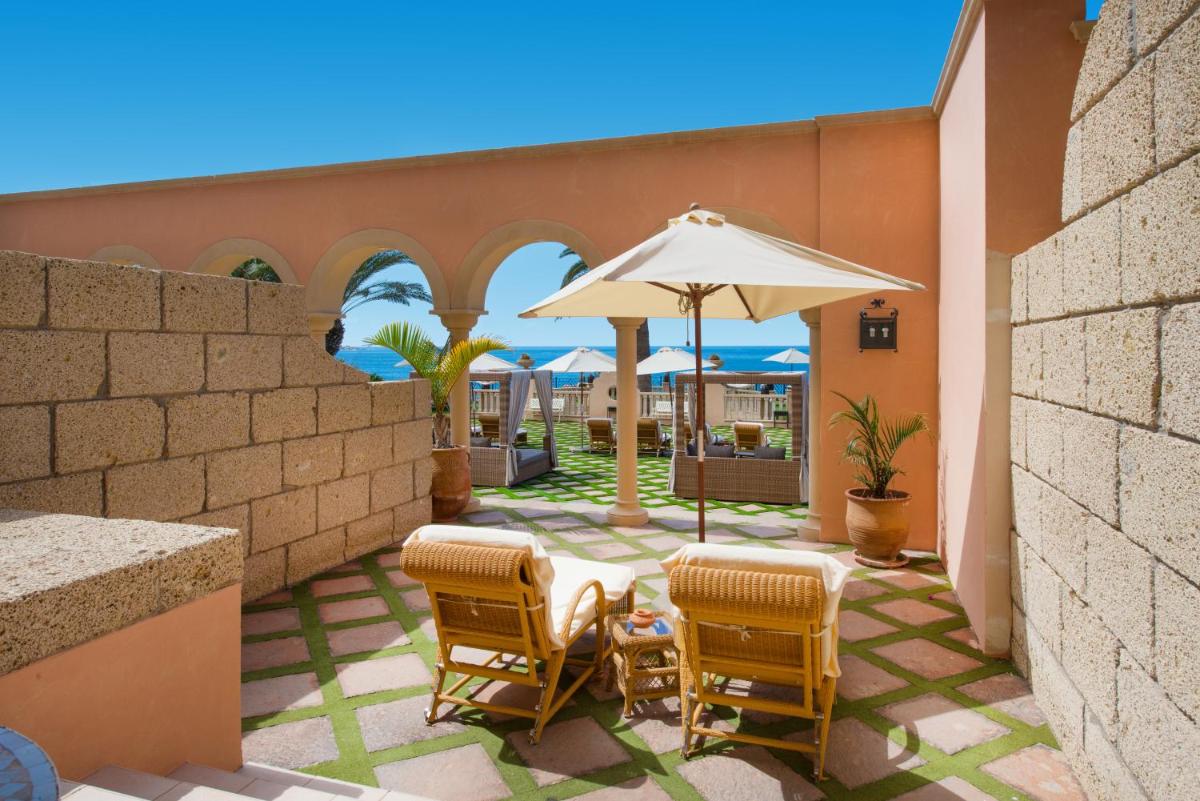 un patio con 2 sillas y una sombrilla en JOIA El Mirador by Iberostar -Adults Only, en Adeje