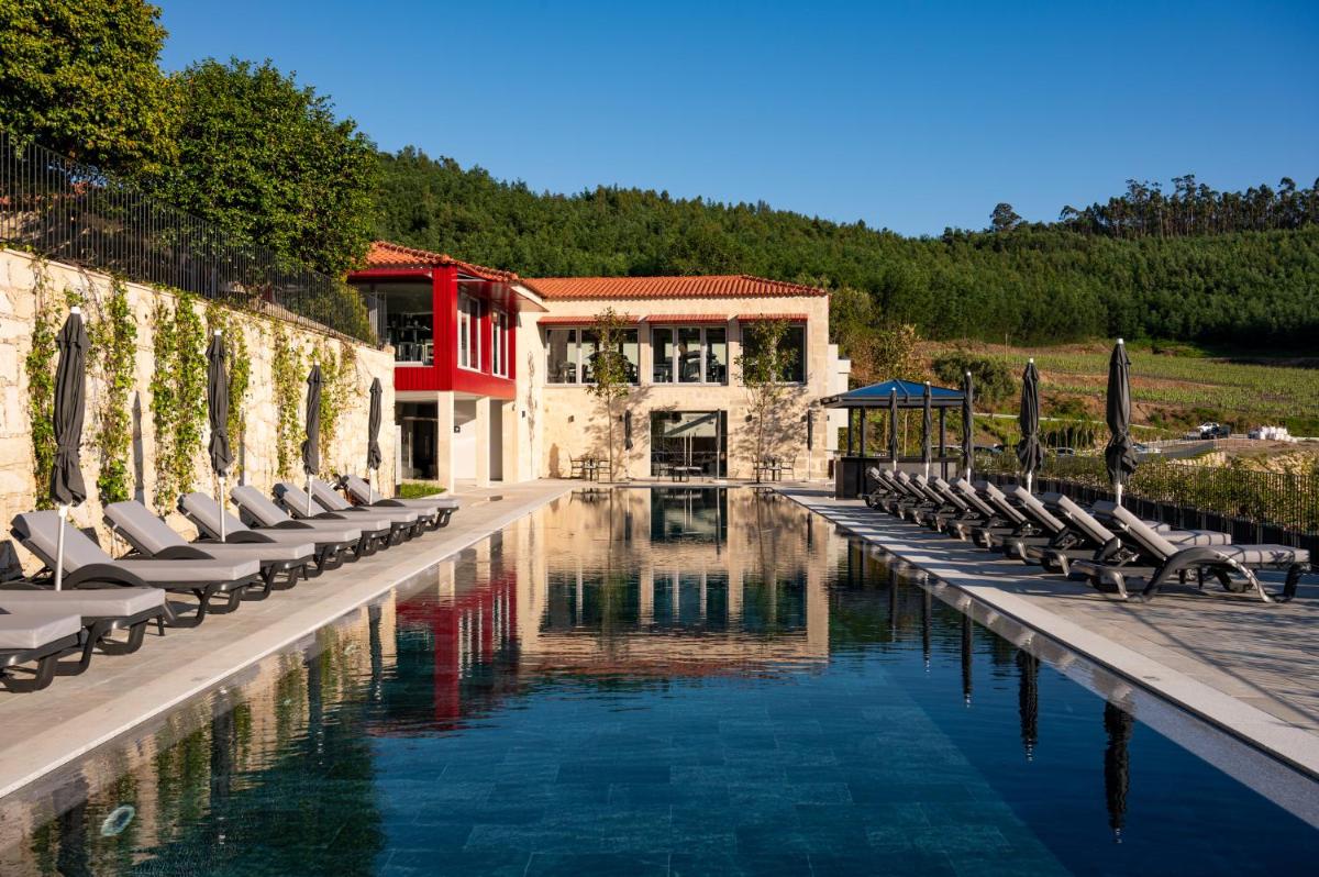 uma piscina com espreguiçadeiras e cadeiras ao lado de um edifício em Vila Gale Collection Ponte de Lima em Ponte de Lima