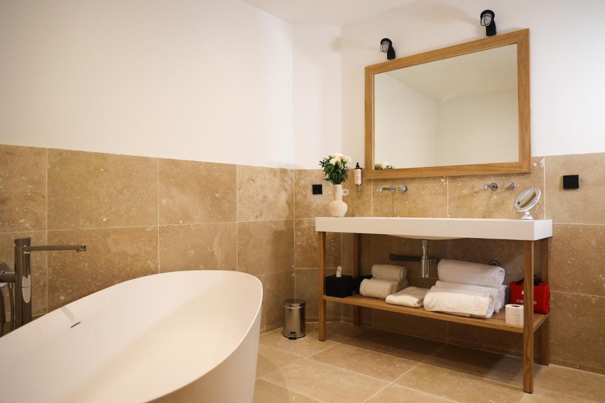une salle de bain avec une baignoire, un lavabo et un miroir dans l'établissement Residence Les Suites Pereire, à Arcachon