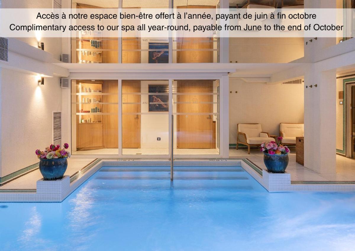 une grande piscine dans une maison avec deux vases bleus dans l'établissement Grand Tonic Hotel & SPA NUXE, à Biarritz