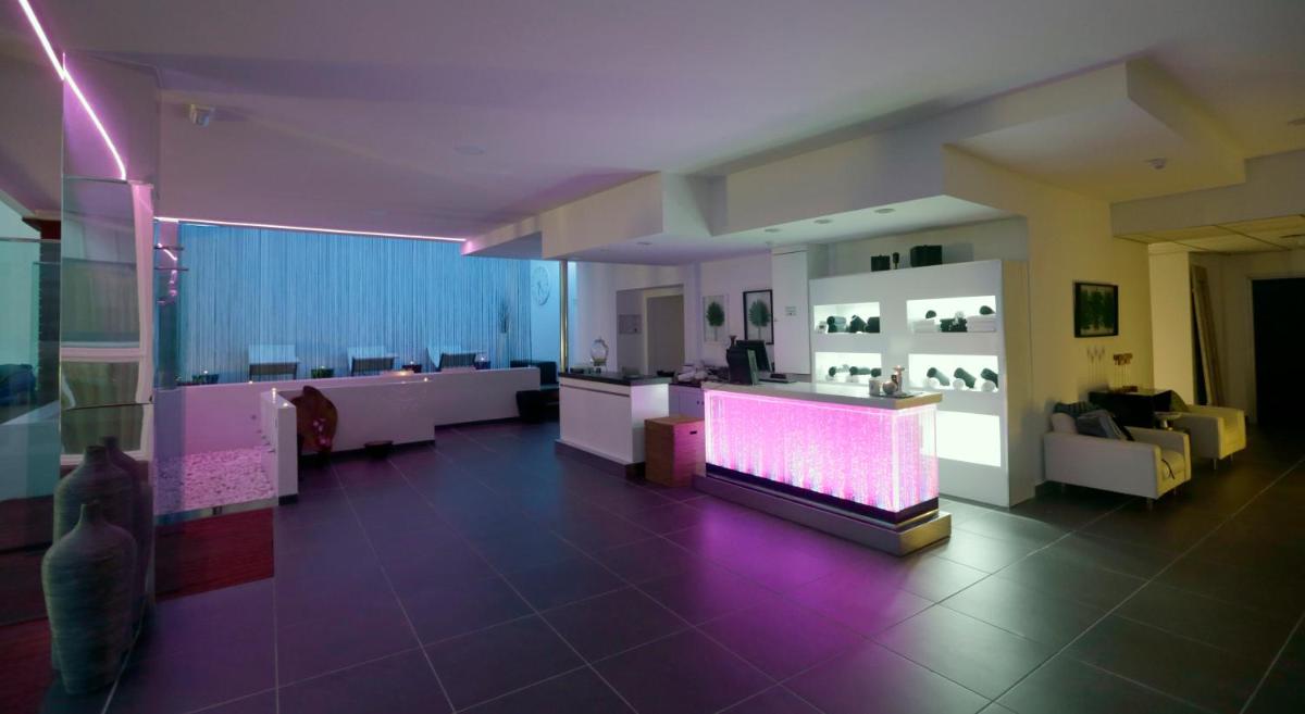 una sala de estar con iluminación púrpura y una habitación con muebles en Hotel Spa Congreso, en Teo