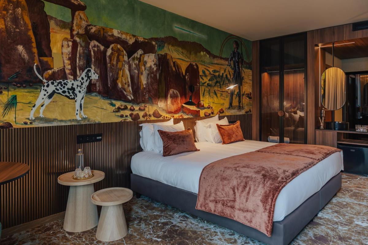 um quarto de hotel com uma cama e um mural em Hotel Leiriartem by Grupo Quinta dos Lagos em Leiria