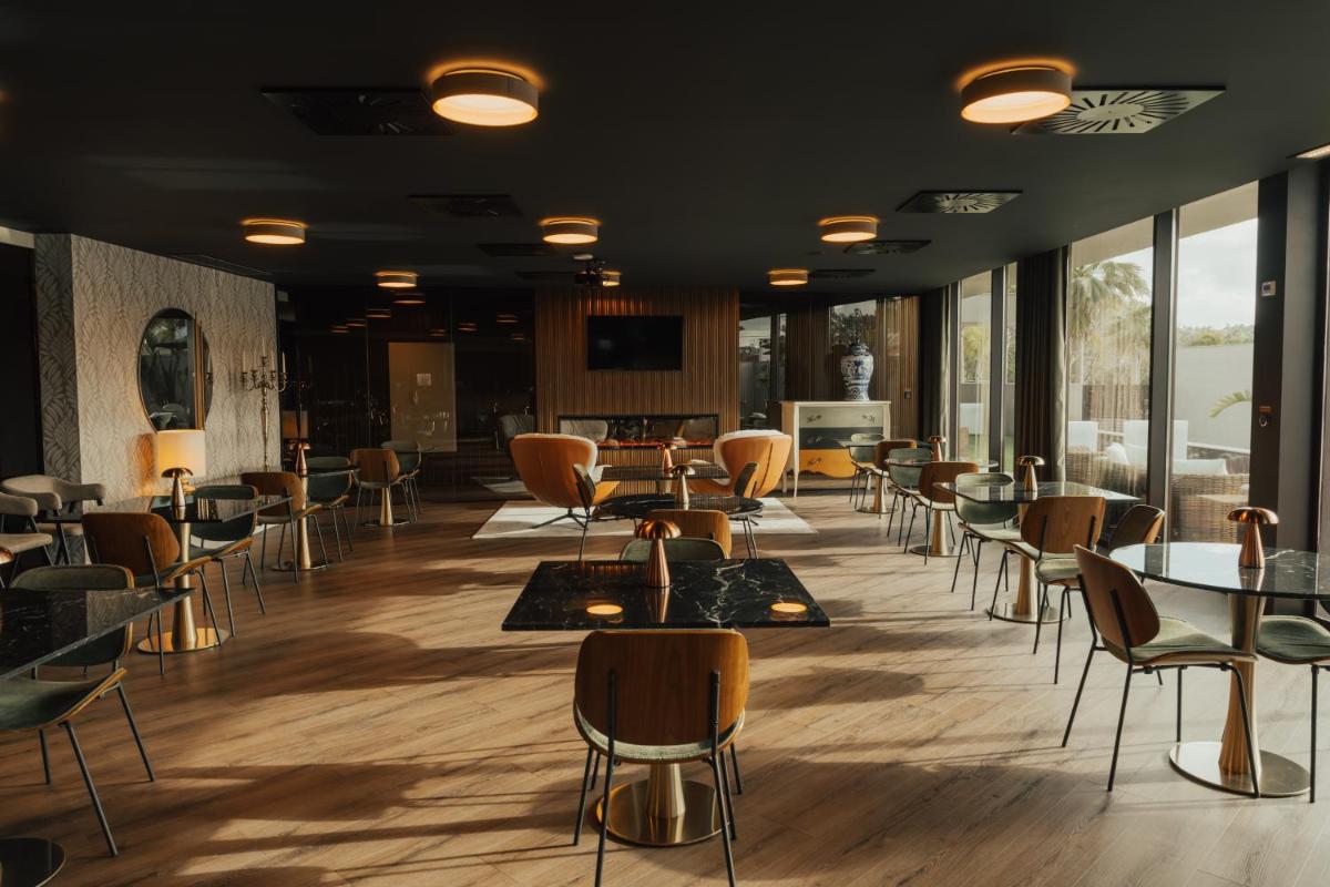 um restaurante com mesas, cadeiras e janelas em Hotel Leiriartem by Grupo Quinta dos Lagos em Leiria