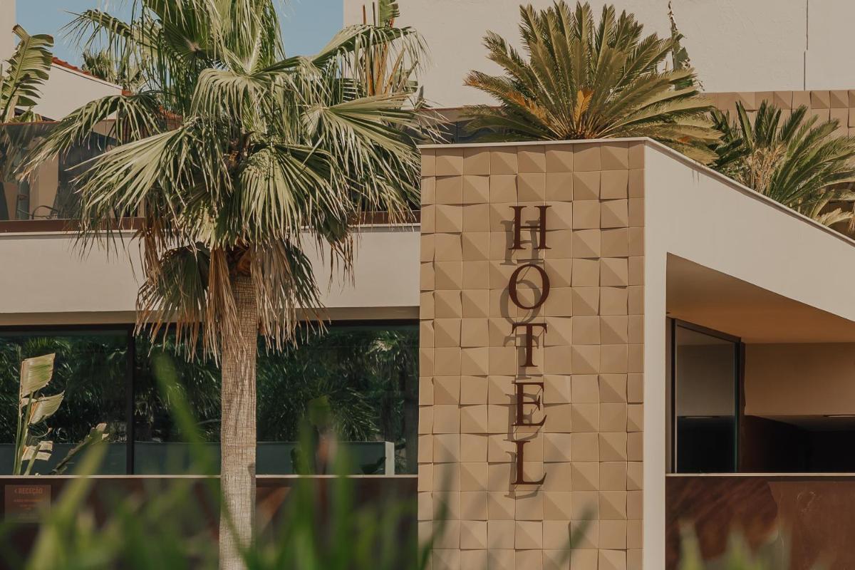 um prédio com uma palmeira na frente em Hotel Leiriartem by Grupo Quinta dos Lagos em Leiria