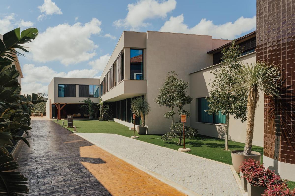 um prédio com palmeiras na frente em Hotel Leiriartem by Grupo Quinta dos Lagos em Leiria