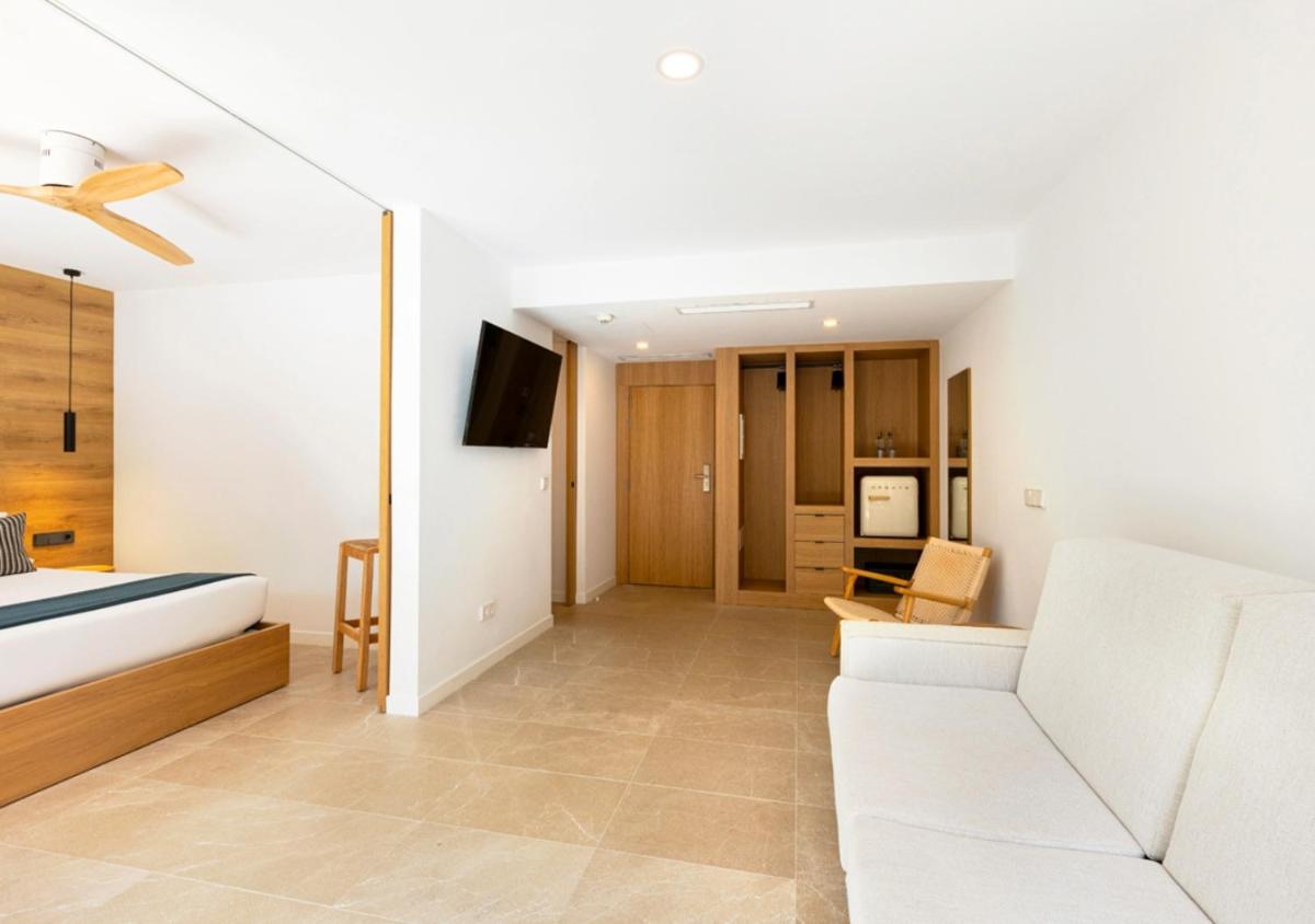 Una sala de estar con un sofá blanco y un televisor. en Las Gaviotas Suites Hotel & Spa, en Playa de Muro