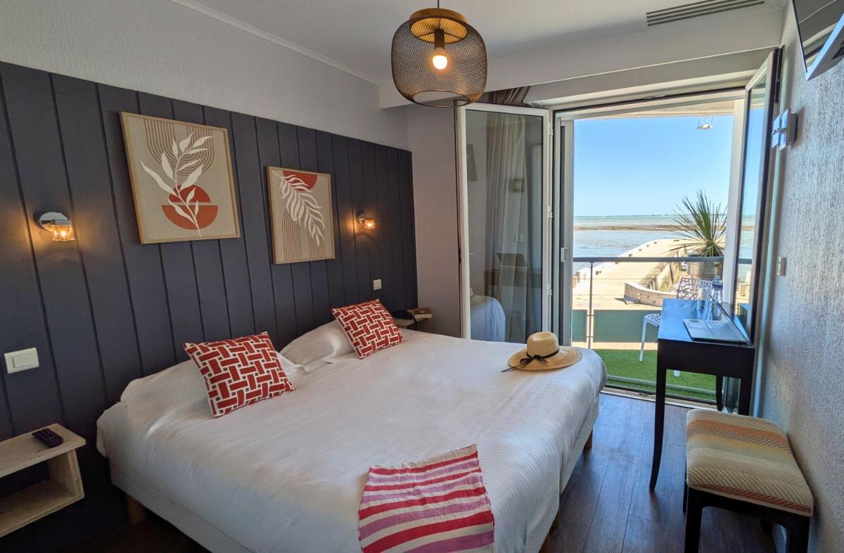 une chambre avec un grand lit avec vue sur l'océan dans l'établissement Hôtel de La Marée - Face à l'océan - Ile de Ré, à Rivedoux-Plage