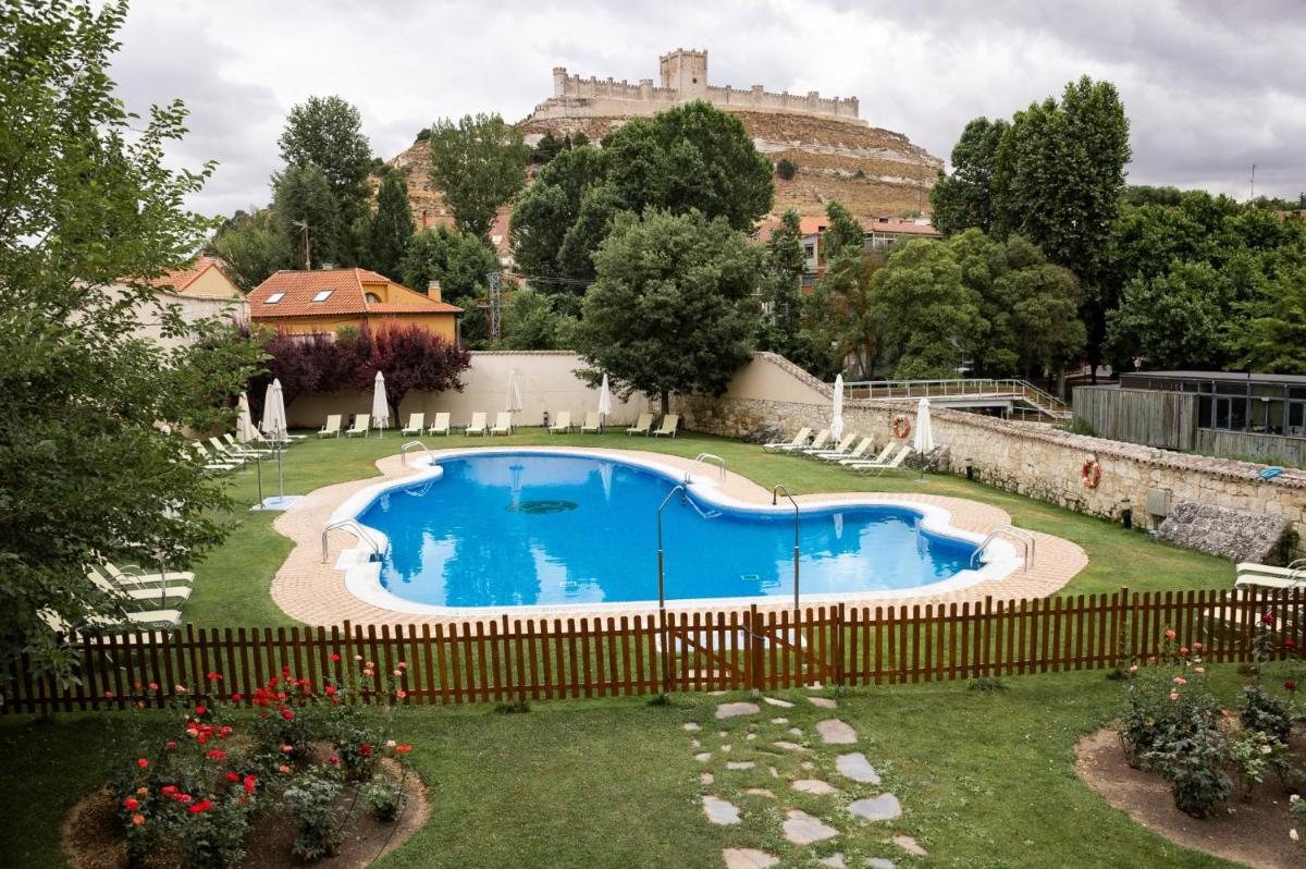 Una piscina en un patio con un castillo al fondo. en AZZ Peñafiel Las Claras Hotel & Spa, en Peñafiel