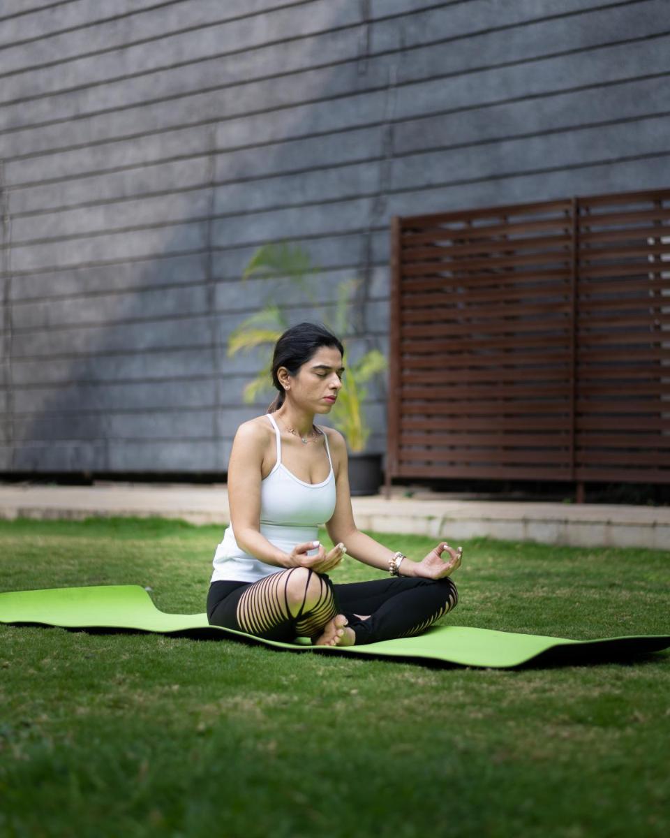 a woman sitting on the grass with a ball at Marriott Suites Pune in Pune