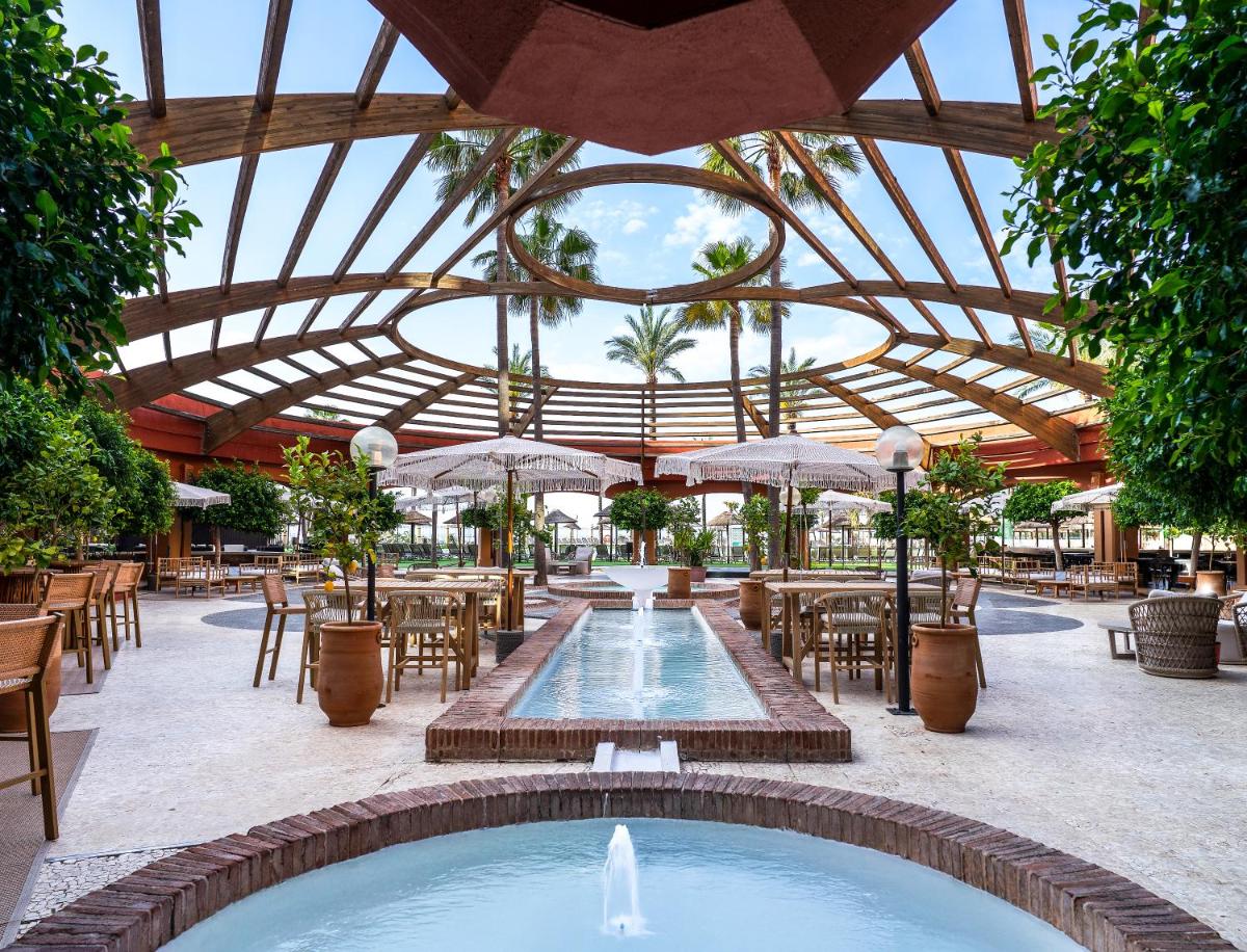 Un restaurante al aire libre con piscina, mesas y sombrillas. en Holiday Premium Resort, en Benalmádena