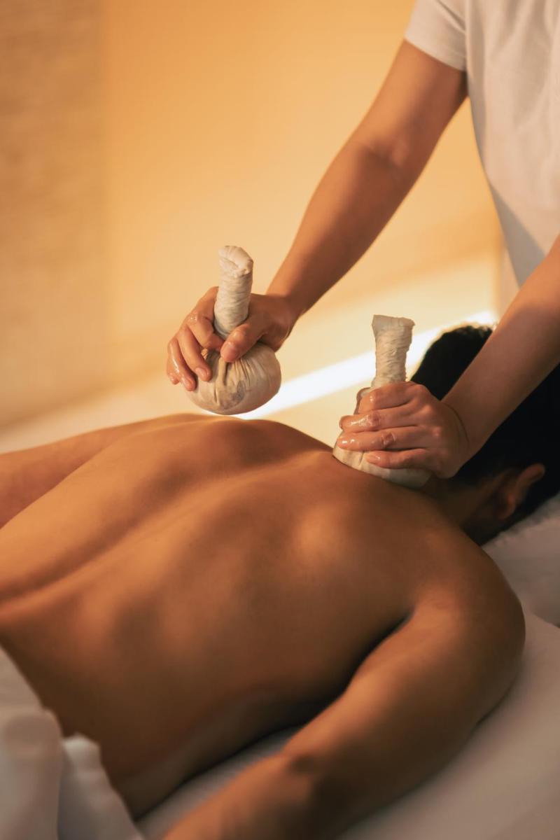 a man getting a massage from a man lying on a bed at Four Seasons Hotel Mumbai in Mumbai