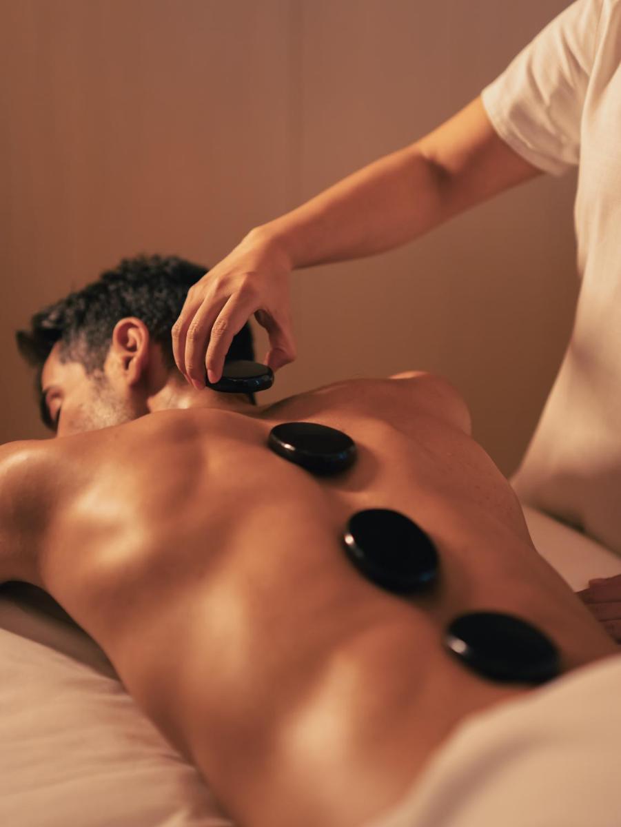 a shirtless man laying on a bed getting a massage at Four Seasons Hotel Mumbai in Mumbai