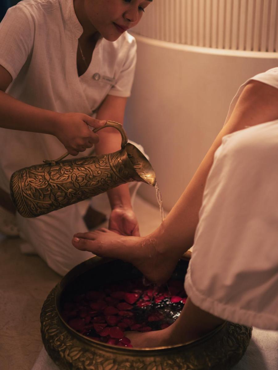 a woman with a hennacovered hand pouring water into a bowl at Four Seasons Hotel Mumbai in Mumbai