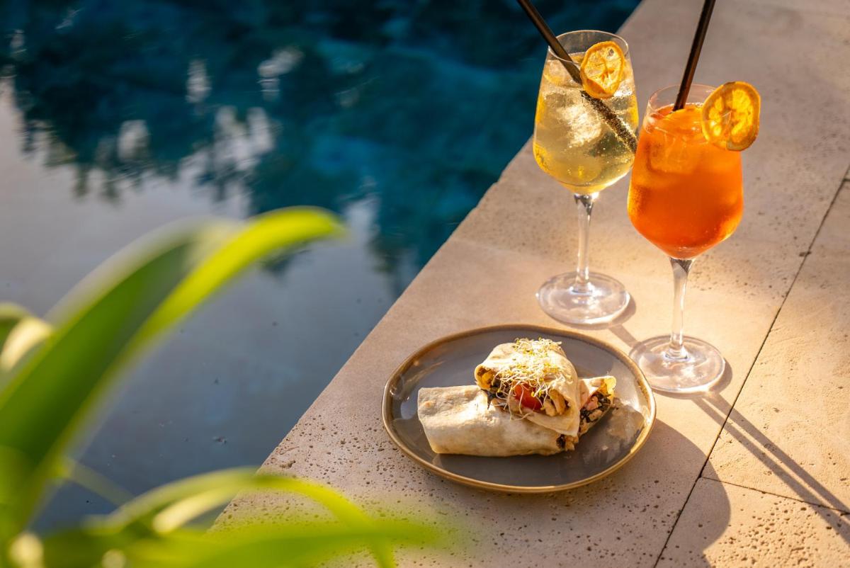 Dos bebidas y un plato de comida junto a una piscina. en Nema Boutique Hotel & Spa, en Artà 54 fotos más
