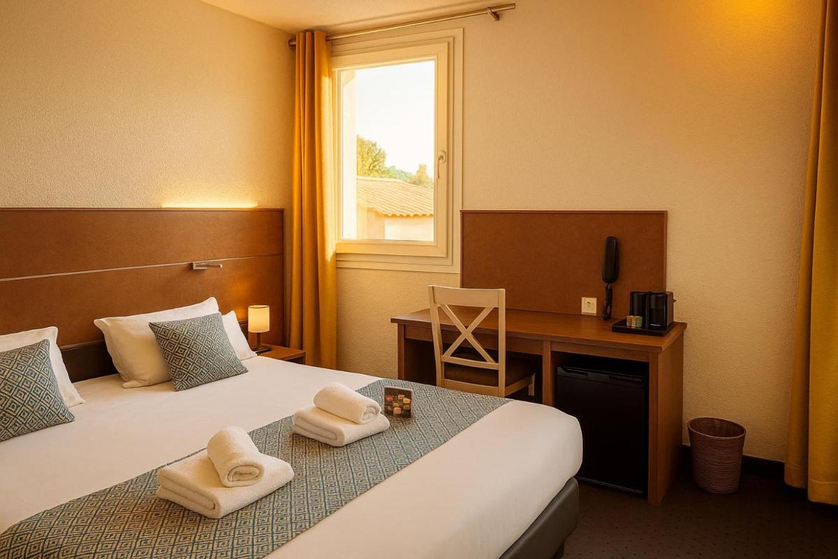 une chambre d'hôtel avec un lit, un bureau et une fenêtre dans l'établissement Hotel & Spa Gil de France Cap d'Agde, au Cap d'Agde